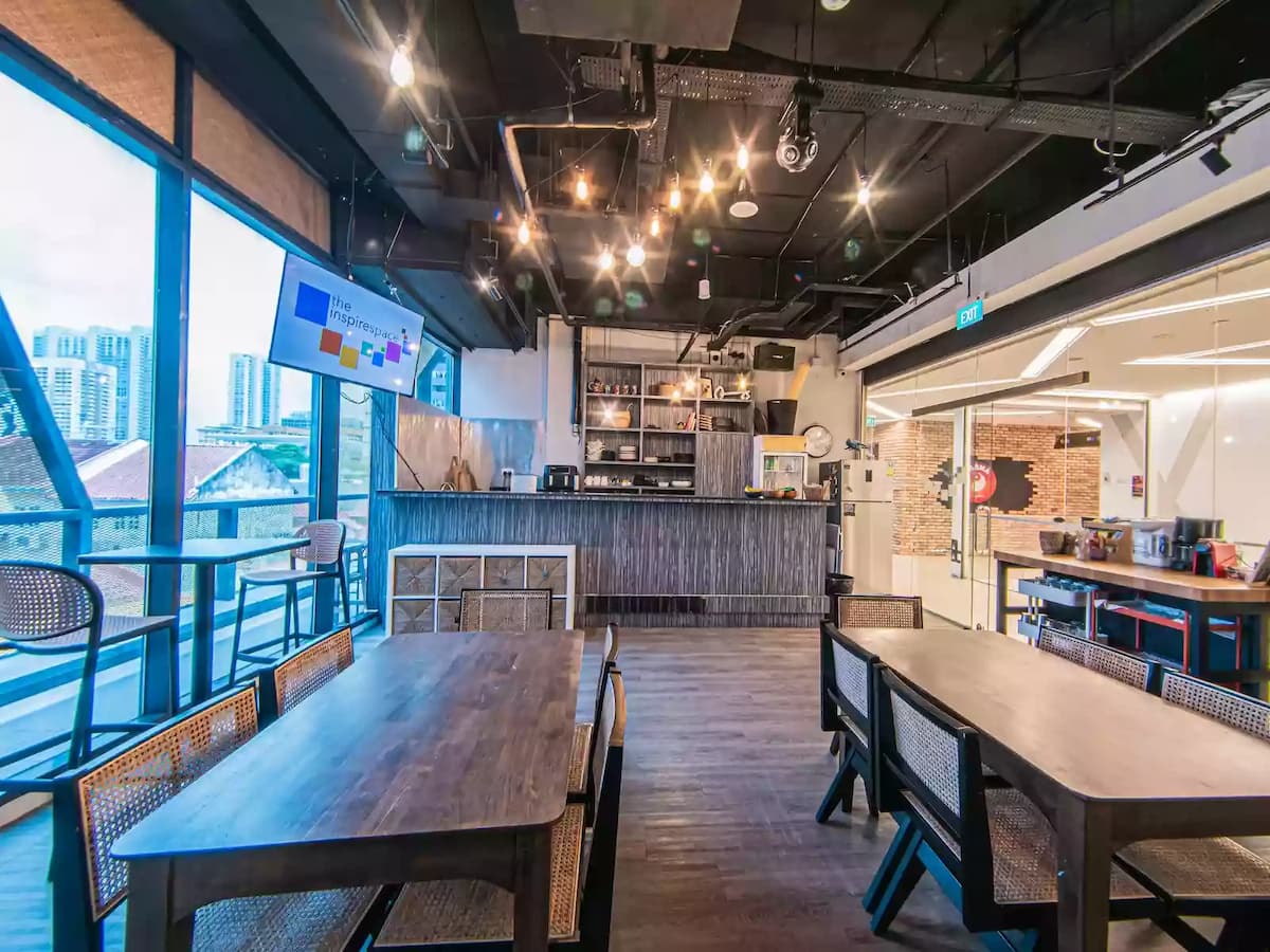 Contemporary workshop and event space with flexible table seating, large windows, and presentation screens—ideal for meetings, workshops, networking sessions, and small corporate events.