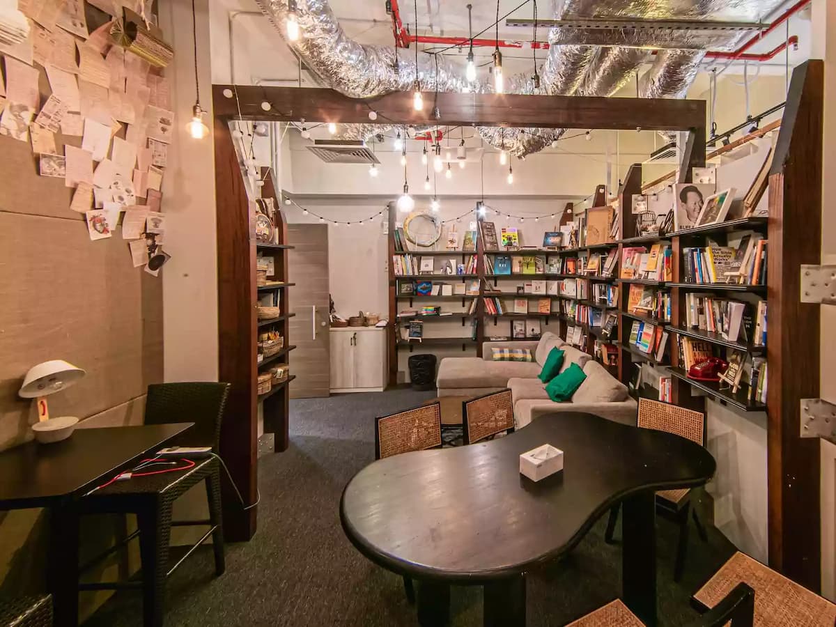 Cozy creative lounge and library-style space featuring bookshelves, a sofa seating area, and a meeting table—ideal for small workshops, team discussions, book clubs, creative brainstorming sessions, or intimate community events.
