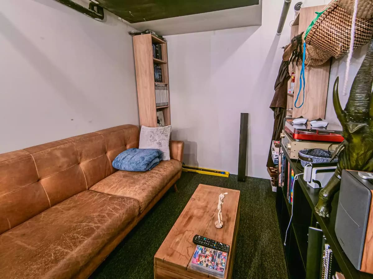 Small cozy lounge or breakout room with a leather sofa, coffee table, and shelving—suitable for casual meetings, creative discussions, content planning sessions, or private relaxation within a studio or workspace.
