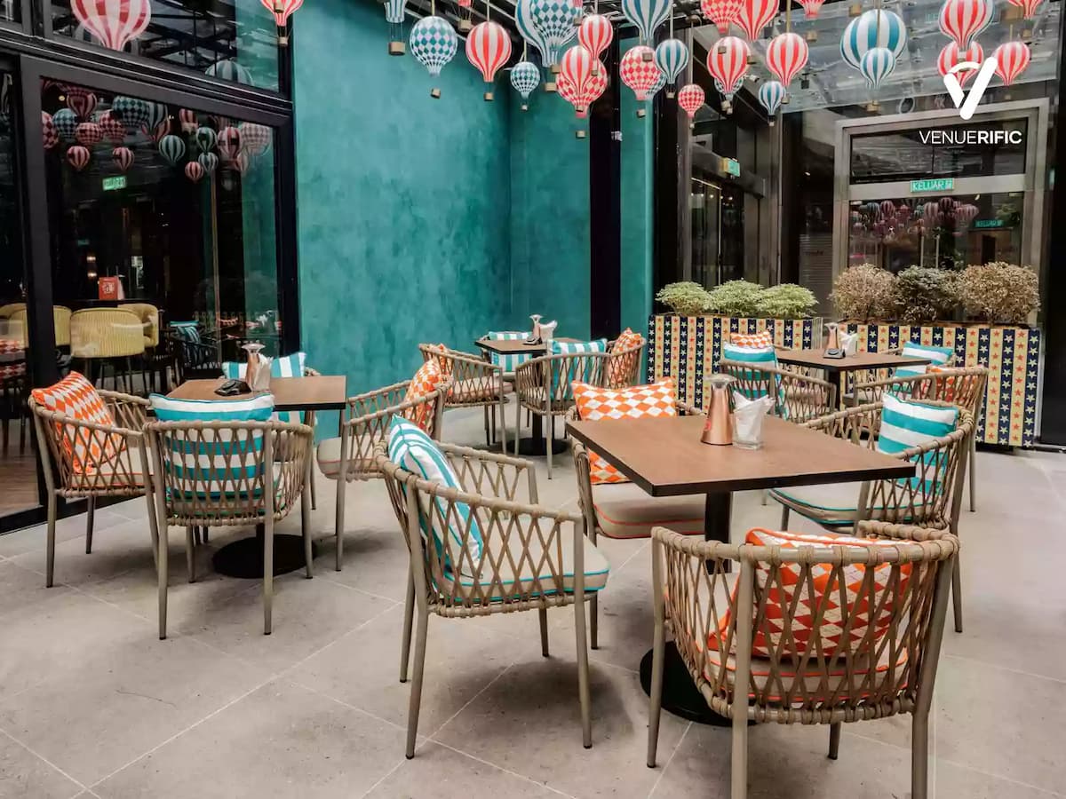 Bright glass-enclosed dining space with colorful hot air balloon decor and rattan seating for casual gatherings.