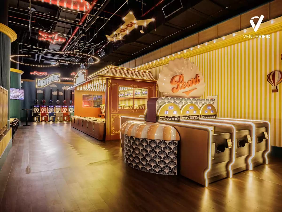 Vibrant carnival-style arcade with bright lighting, game booths, and retro fairground decor.
