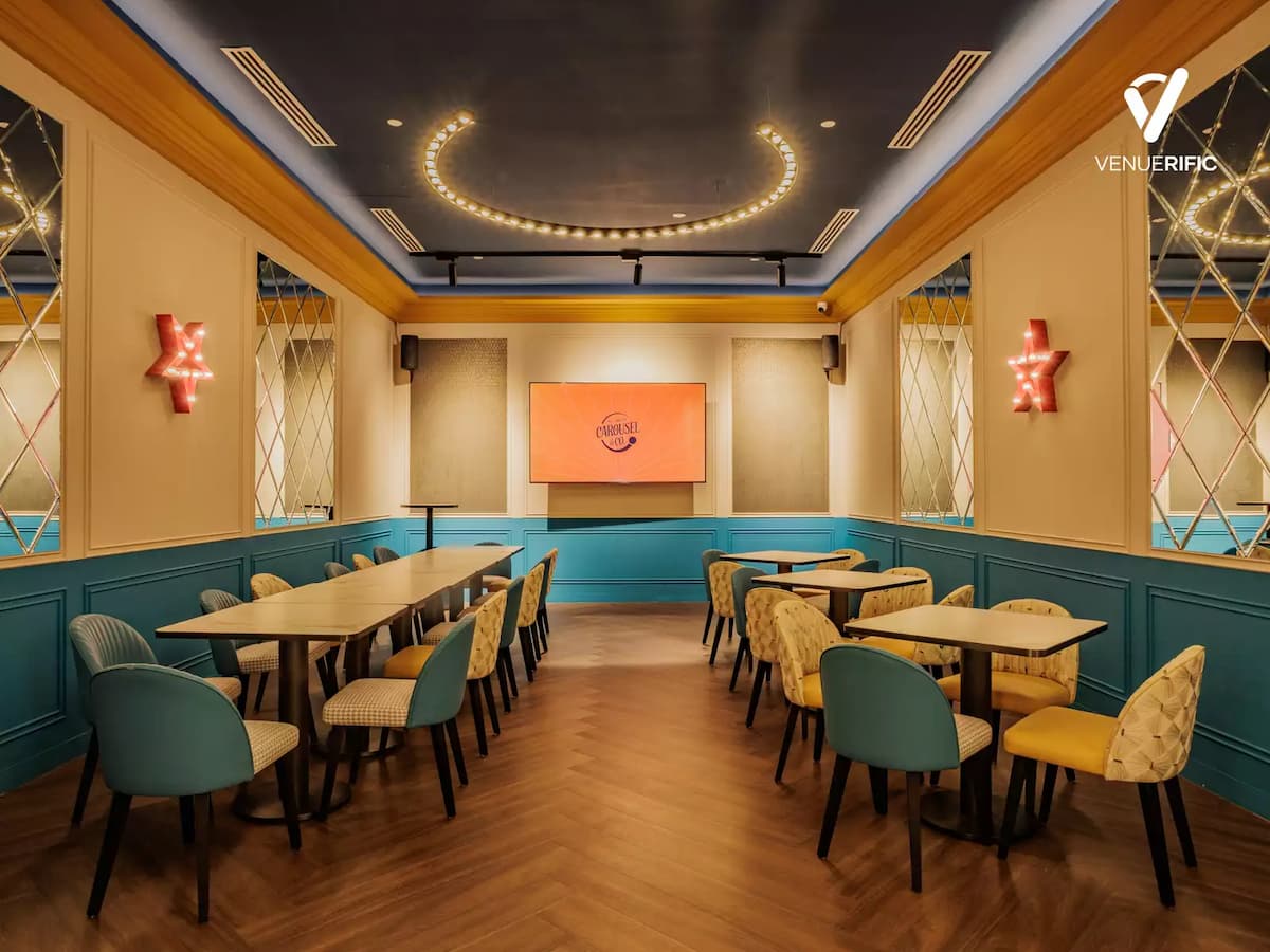 Elegant event room with teal accents, long tables, warm lighting, and a display screen for meetings or dining.