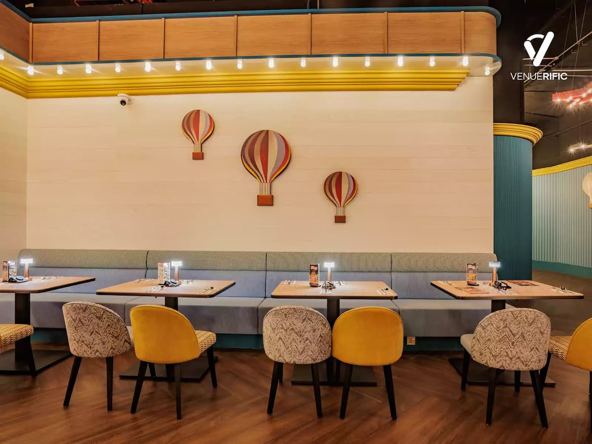 Cozy dining area with warm lighting, plush seating, and hot air balloon wall decor for casual gatherings.