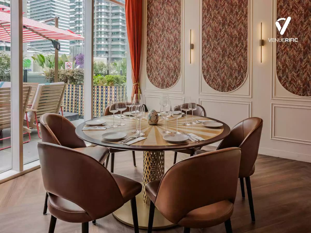 Private dining space with a round table, elegant seating, and floor-to-ceiling windows overlooking an outdoor terrace.